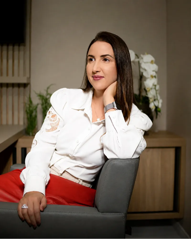 Kelly Ferreira, advogada, sentada em seu escritório, de camisa branca